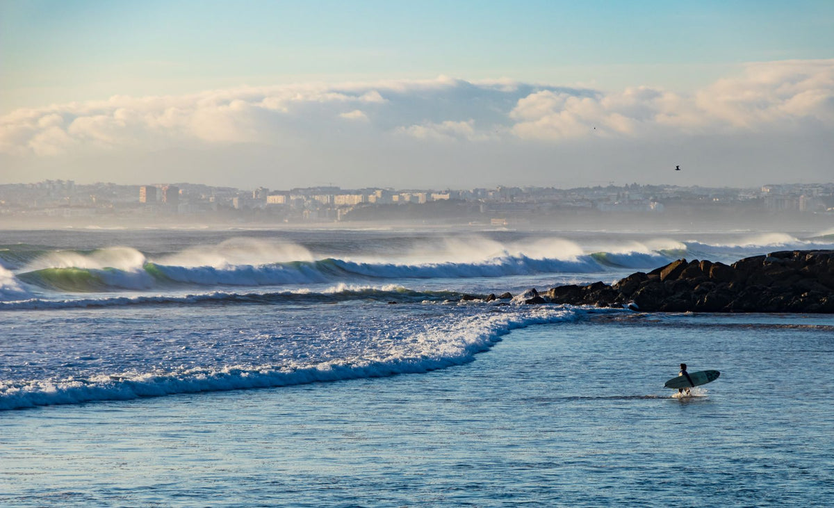 A surfer approaching Atlantic waves at Costa da Caparica, Portugal. Photo by Marc Winter via Pexels.